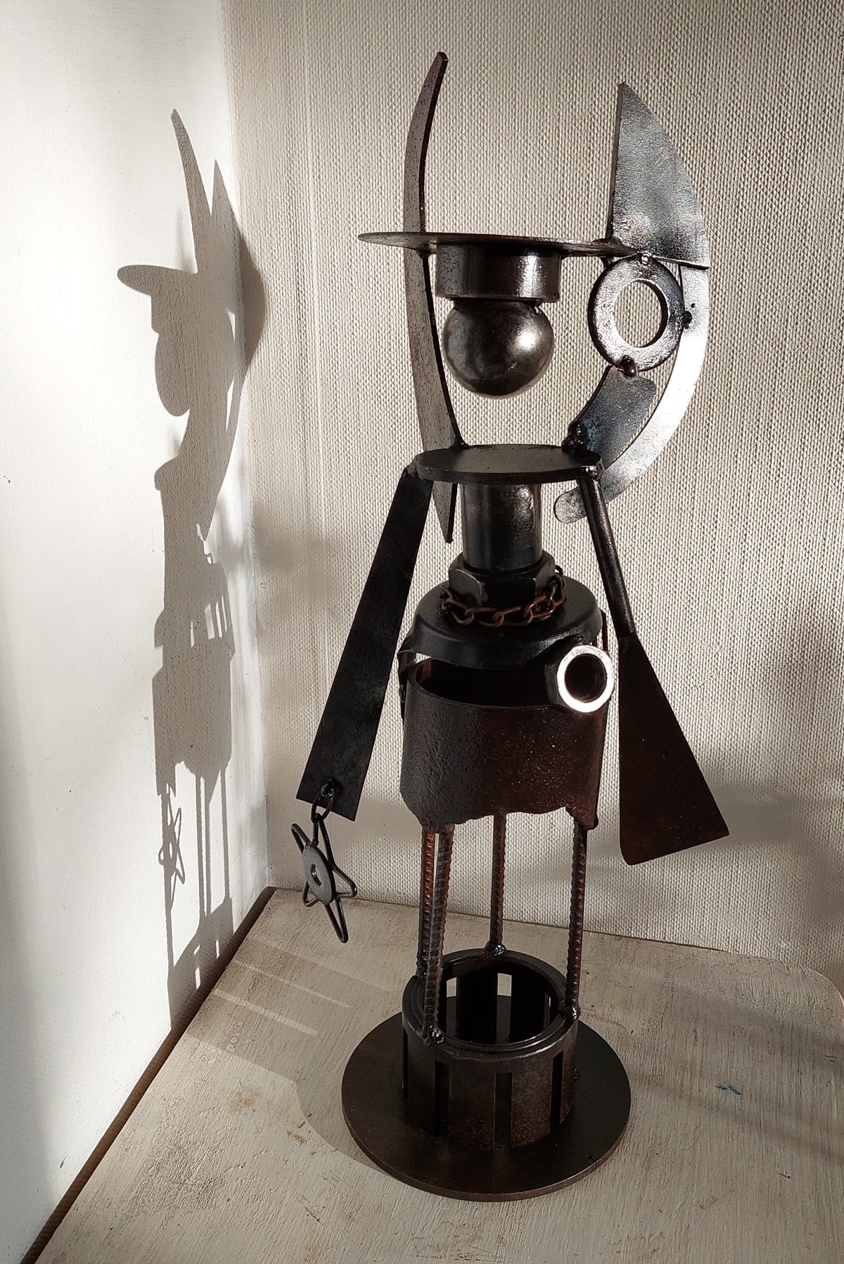 Sternenengel aus Metall mit baumelndem Stern an der Hand und Schattenwurf an der Wand